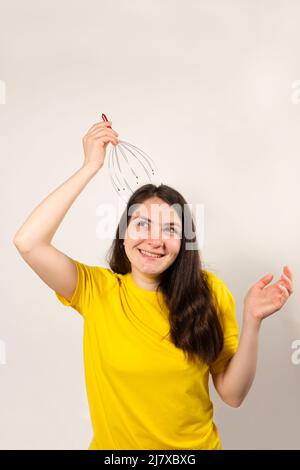 A woman with a metal flexible massager for self-massage of the head on a white background. Stock Photo