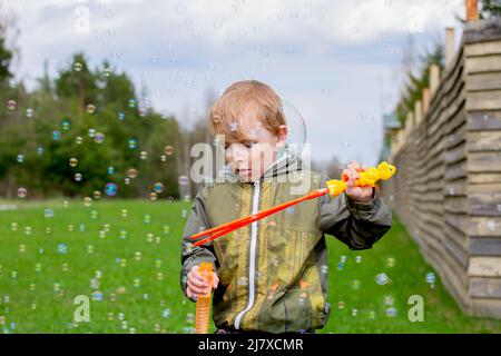 A boy blows soap bubbles on the street Stock Photo