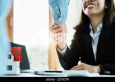 Laws, contracts, mortgages, clients join hands with real estate agents congratulating real estate agents on home and land purchase agreements with Stock Photo