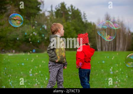 Children playing on the green grass with soap bubbles Stock Photo