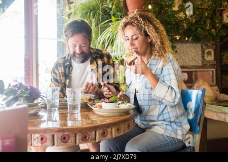 Adult couple eating together at the restaurant. Caucasian man and woman having lunch sitting at the table. Hipster style people in brunch leisure acti Stock Photo