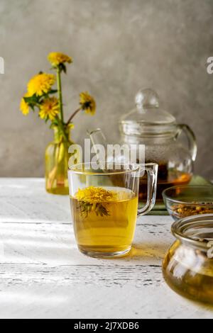 Healthy herbal tea from dandelions on the white wooden table with tea pot, dandelion flowers, honey Stock Photo