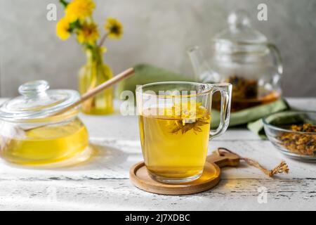 Dandelion tea and honey on the white wooden table with tea pot, dandelion flowers, dry mix for tea Stock Photo