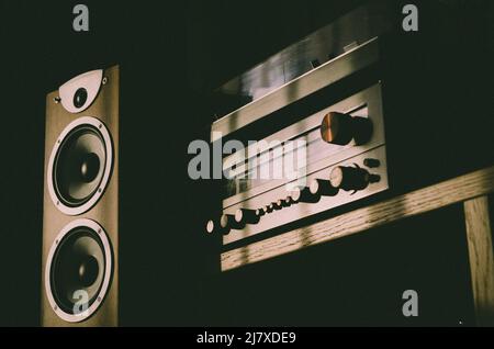 Home sound system - wooden speaker with two white membrane drivers, vintage stereo receiver and turntable placed on the top of it. Audio equipment. Stock Photo