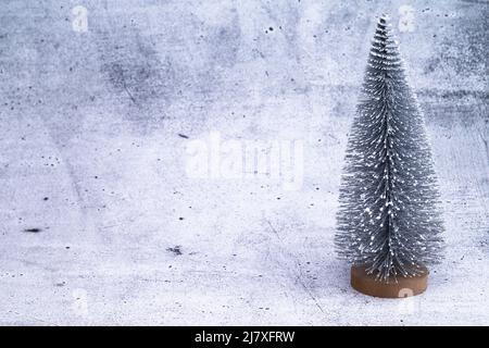 The photo shows a miniature Christmas tree on concrete background Stock Photo