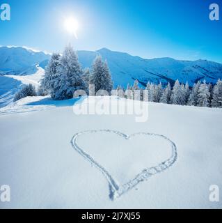 Heart symbol in snow with snowy firs and mountains on background Stock Photo