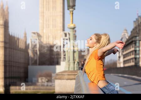 A happy tourist woman stands on the Westminster Bridge in London Stock Photo
