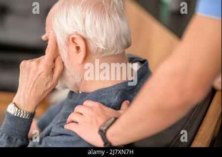 Experienced in-home caretaker comforting an elderly person Stock Photo