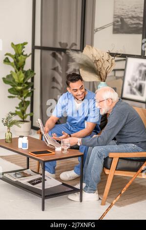 Pensioner discussing news with his in-home caretaker Stock Photo