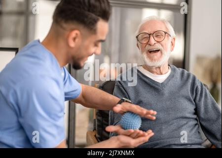 Patient having his hand massaged with a spiky massage ball Stock Photo