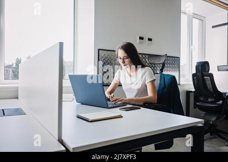 Young female programmer web developer working on computer software in modern office. Web Designer Woman working at her desk in open plan office Stock Photo