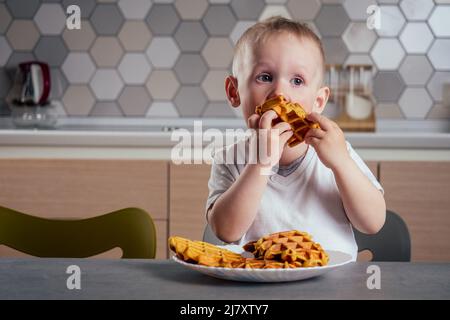 son preparing waffles in kitchen Belgian waffles waffle iron Stock Photo