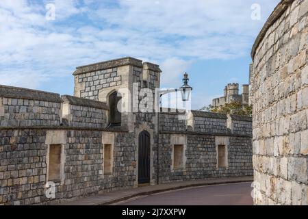 Ancient walls of a castle against a blue sky with ornate wall lamp and arched door Stock Photo
