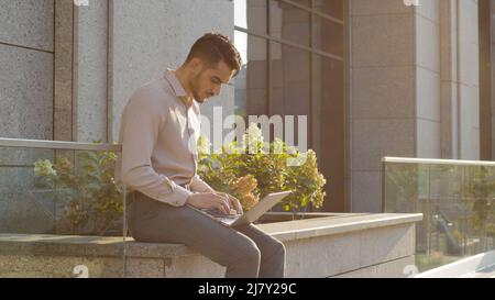 Professional successful young freelancer male specialist programmer student business man in stylish formal clothes boss leader sitting on street near Stock Photo