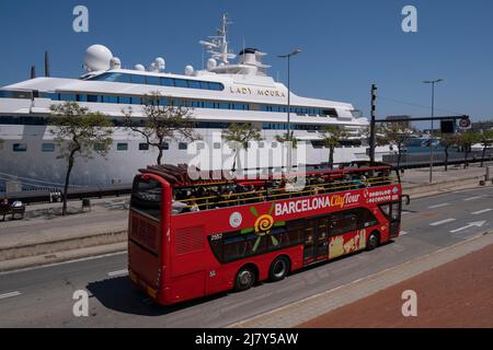 A Barcelona City Tour Bus is seen passing in front of the luxurious private yacht Lady Moura docked in the port of Barcelona. Built by the German company Blohm + Voss, the Lady Moura was the ninth largest yacht when she was launched in 1990. Stock Photo