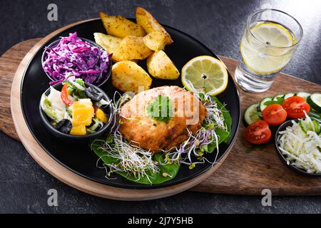 Pulled chicken cutlet coated with breadcrumbs with potatoes and vegetable salads Stock Photo