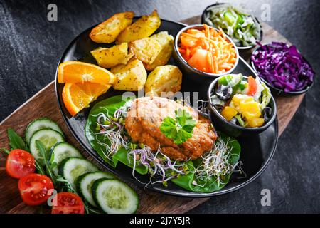 Pulled chicken cutlet coated with breadcrumbs with potatoes and vegetable salads Stock Photo