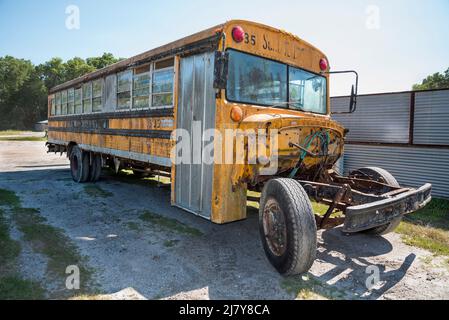 Old school bus parked in front of a scrap metal facility in North Central Florida. Stock Photo