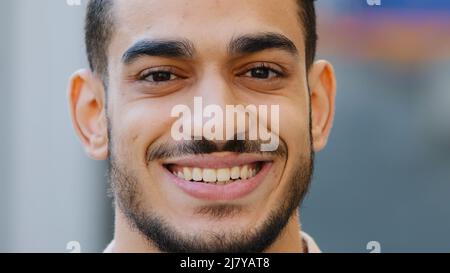 Close up outdoors head male portrait young hispanic happy smiling handsome business man standing in city. Healthy bearded guy arabic client with Stock Photo