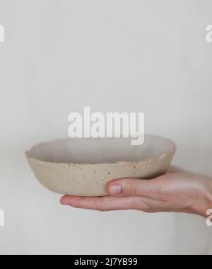Hands holding ceramic bowl isolated on white background. Handmade ceramic tableware Stock Photo