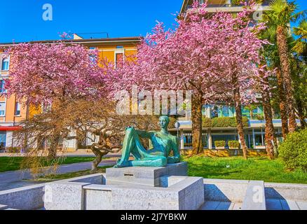 The statue fountain and blooming cherry trees in Parchetto Lanchetta Park of Lugano, Switzerland Stock Photo