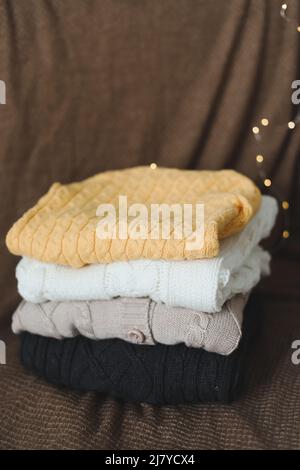 a stack of warm woolen knitted sweaters on a dark background. Stock Photo