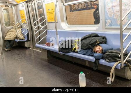 Homeless men sleep on an E line subway train in New York on Sunday ...