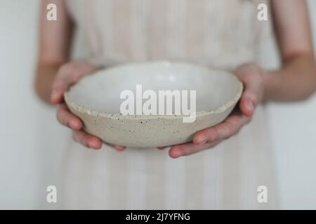Hands holding ceramic bowl isolated on white background. Handmade ceramic tableware and pottery Stock Photo