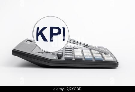 Key performance indicators. Magnifying glass with KPI letters at calculator. Calculating and analysis of metrics for monitoring progress in business objectives achievement. Strategic planning. High quality photo Stock Photo
