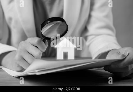 Customer studying real estate purchase, lease, loan or mortgage agreement. Woman hands with magnifying glass closeup. Careful deal examination before signing. Black and white. High quality photo Stock Photo