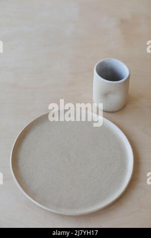 ceramic cup and plates on a wooden table top view. minimalist set of handmade ceramic tableware and pottery Stock Photo