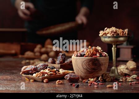 Various dried fruits and nuts are in a wooden bowl on a kitchen table. Selective focus. Stock Photo
