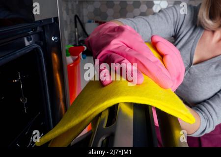 Young woman cleaning oven in the kitchen Stock Photo