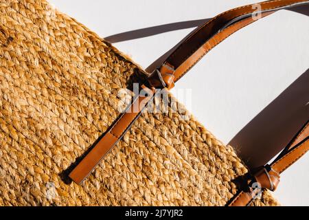 Stylish straw beach bag on white background, top view. Summer accessories, natural sunlight Stock Photo
