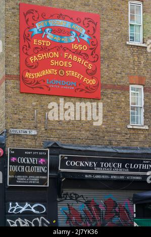 Advertising sign for Petticoat Lane market on wall above Cockney Touch Clothing store in Goulston Street, Whitechapel, London, England, UK Stock Photo