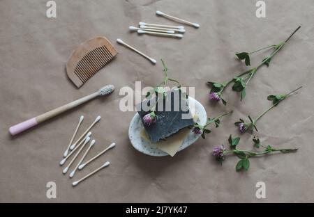 Handmade natural soap, wooden toothbrushes, cotton swabs and hairbrush on craft paper background top view with copyspace. Concept of plastic free and Stock Photo