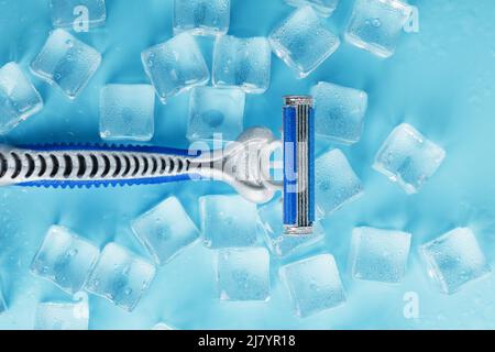 Shaving machine on a blue background with ice cubes. The concept of cleanliness and frosty freshness Stock Photo