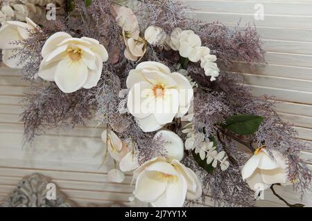 Bouquet of lovely white ornamental flower made of material and plastic hanging on a wall as part of interior Stock Photo