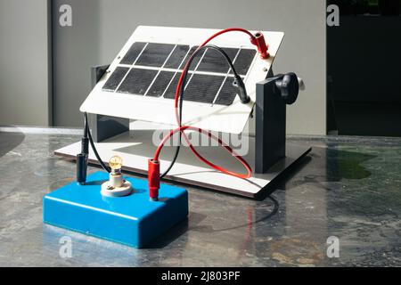 Solar panel to which a small light bulb is connected. Used as a demonstration model in science class. Stock Photo