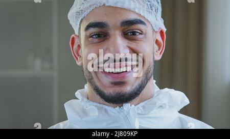 Smiling doctor arabic surgeon hispanic nurse medical worker in special uniform hat looks at camera smile toothy after successful operation working Stock Photo