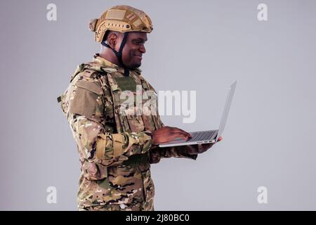 African American soldier smiles while typing a computer videocall with wife and child Stock Photo