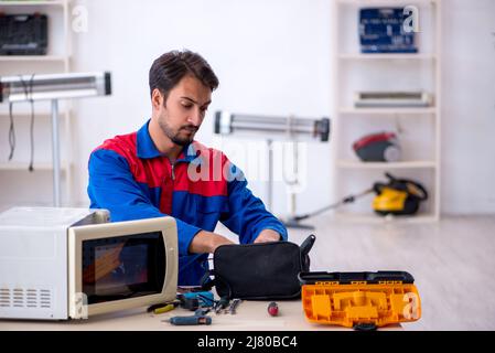 Young repairman repairing oven at workshop Stock Photo