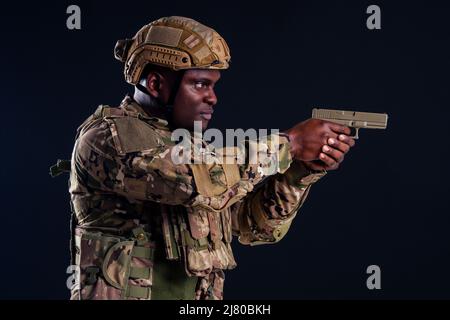 american man in camouflage suit aiming with a pistol studio shot Stock Photo