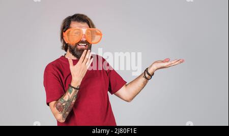 Surprised man in funny big glasses presenting product hold something on palm. Season Sale, discount. Stock Photo