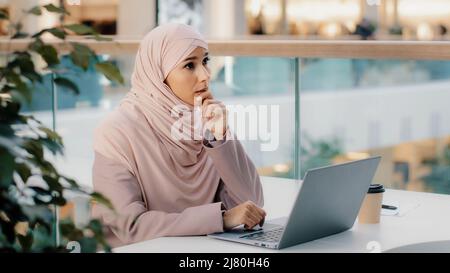 Serious arab woman in hijab working remotely typing on laptop writing book article muslim writer journalist female student creative personality Stock Photo