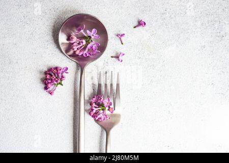 Overhead view of a fork and spoon decorated with lilac flower blossom Stock Photo