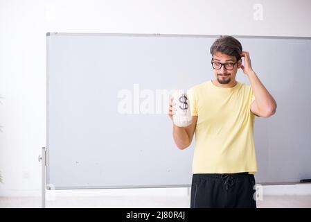 Young student holding moneybag in front of whiteboard Stock Photo