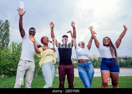 group of five smiling african-american men and women walking outside cloudy weather near the lake,exchange students in Russia team work Stock Photo