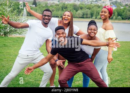 group of five smiling african-american men and women walking outside cloudy weather near the lake,exchange students in Russia Stock Photo