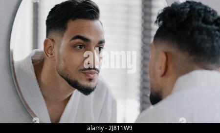 Mirror reflection portrait arabian arab indian bearded man washing face male wet face with hot cold water guy morning showering skincare routine Stock Photo